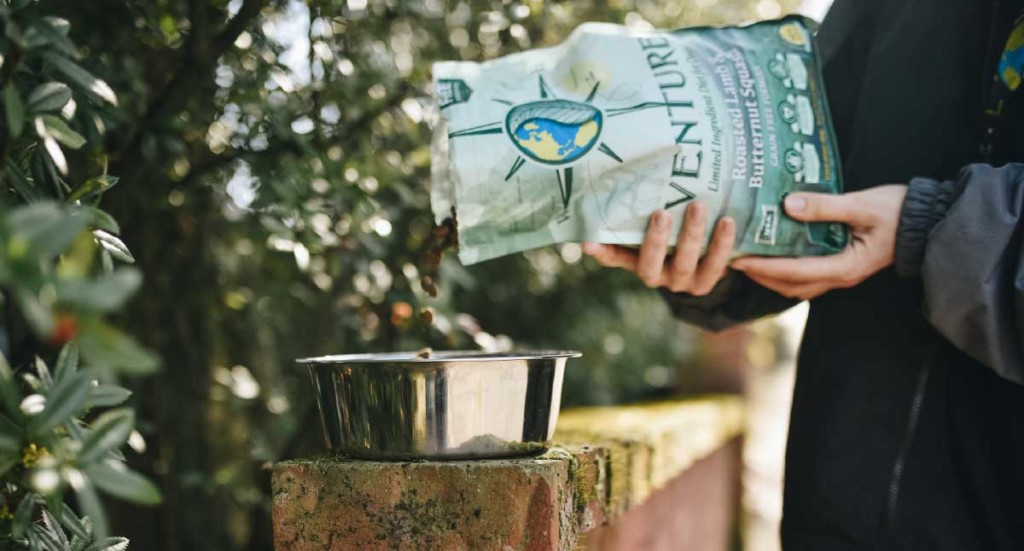 A person pouring Venture dog food into a dog bowl